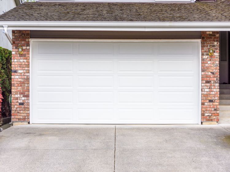 White garage door on a brick home in Newberg OR after a garage door repair performed by All About Garage Doors