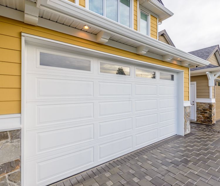 Bright yellow and stone home gets a garage door replacement by All About Garage Doors in Newberg OR