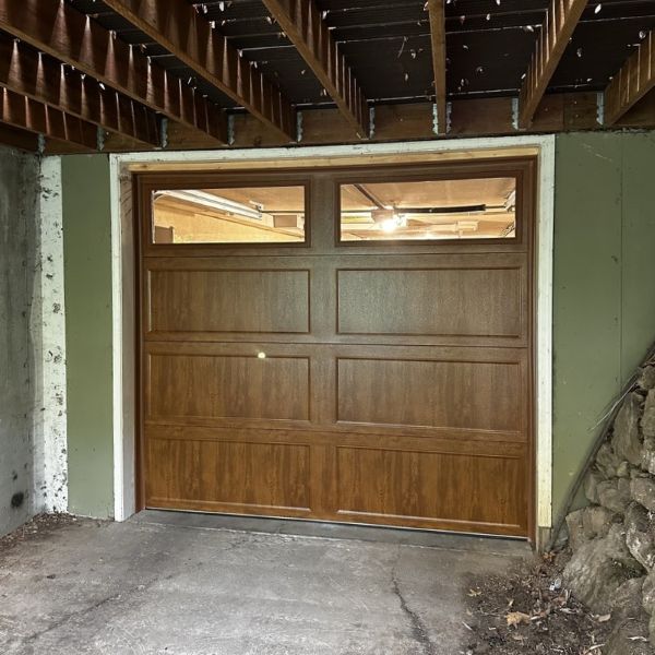 Green home with wooden garage door receives a garage door repair from All About Garage Doors in Garden Home OR